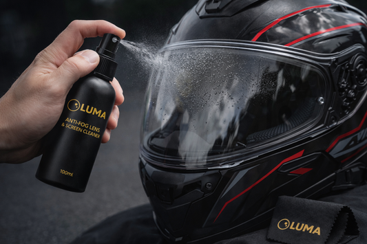 Person cleaning a motorcycle helmet with Luma anti-fog lens cleaner.